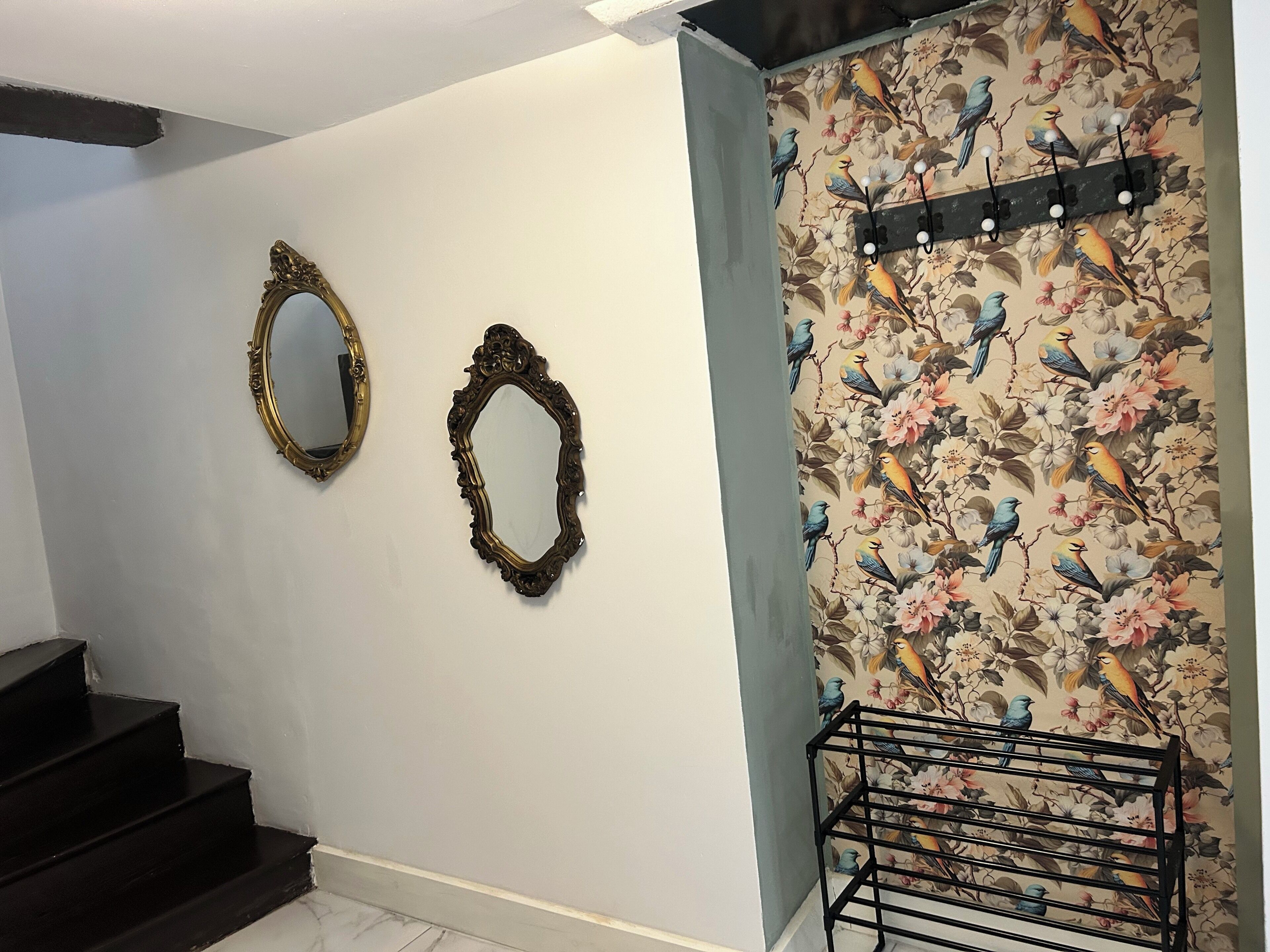 Una escalera con un espejo adosado a la pared y un estante decorativo con ganchos.