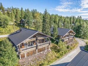 A cabin with a balcony, surrounded by dense forest.