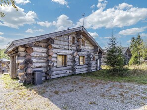 Una cabana de fusta amb una placa identificadora visible, finestres i un camí de grava.