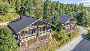 Ett hotell i stugstil med en framträdande byggnad i form av en timmerstuga, en täckt veranda och utsikt över ett skogsområde.