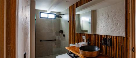 A modern bathroom with a glass-enclosed shower, a wooden vanity, and a large mirror.