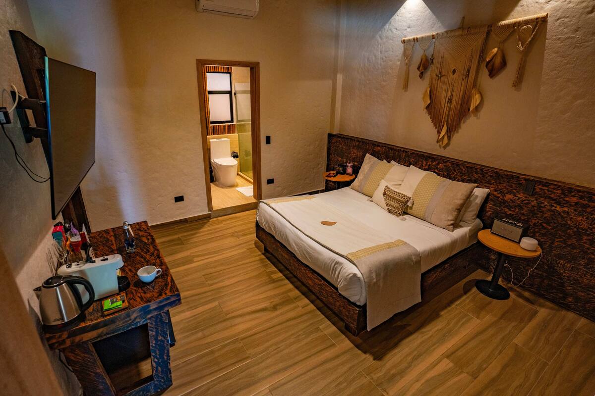 A hotel room with a bed, bedside table, TV, and a view of the bathroom.
