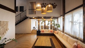 A spacious living area with a large sectional sofa, a wooden coffee table, and a staircase leading to an upper level. - Casa Malva Villas (Buenavista)