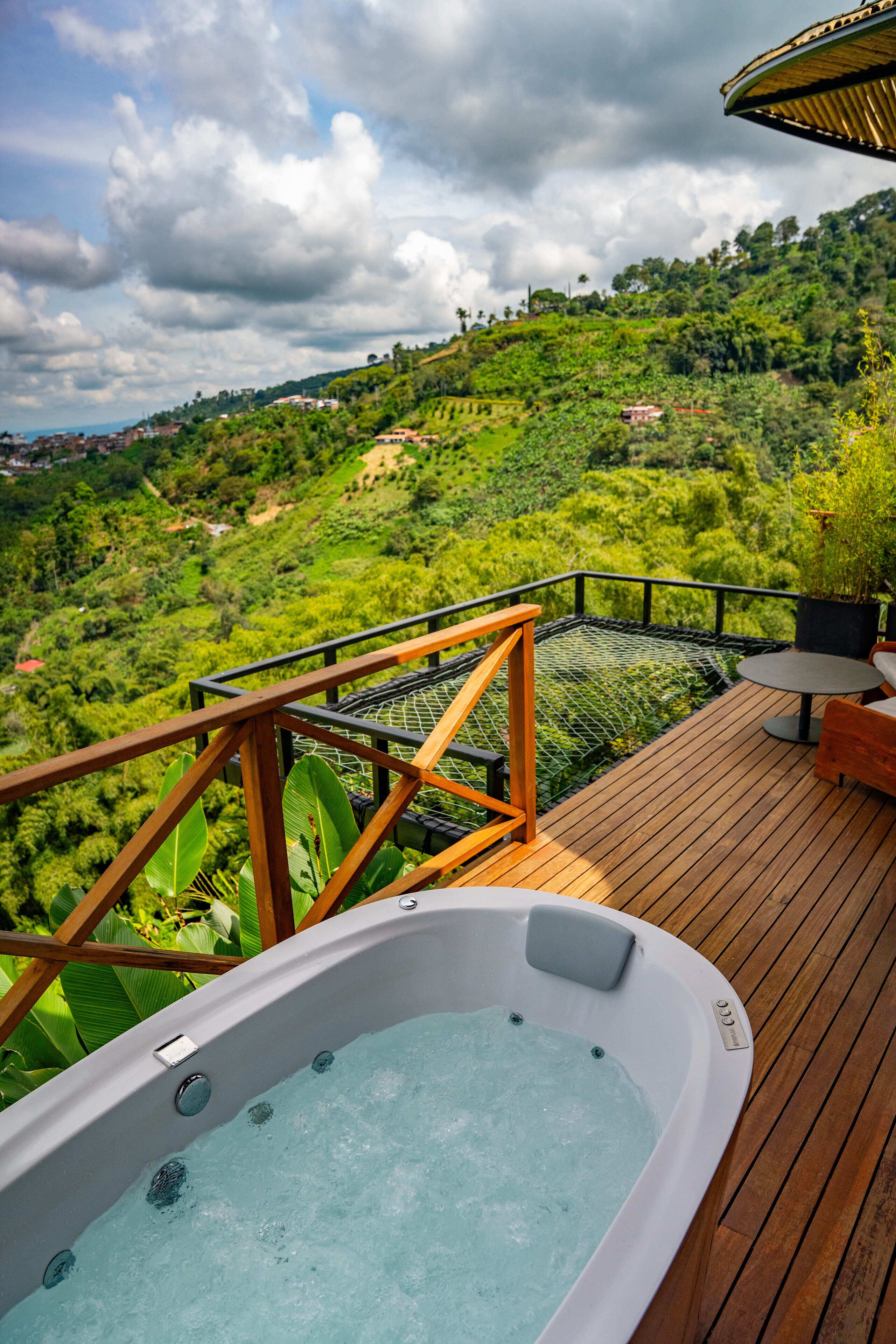 A hot tub on a wooden deck with a view of a lush green landscape.