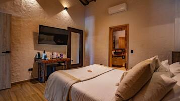 A bedroom with a wooden bed, a bedside table with a lamp, a mirror, and an air conditioning unit on the wall.