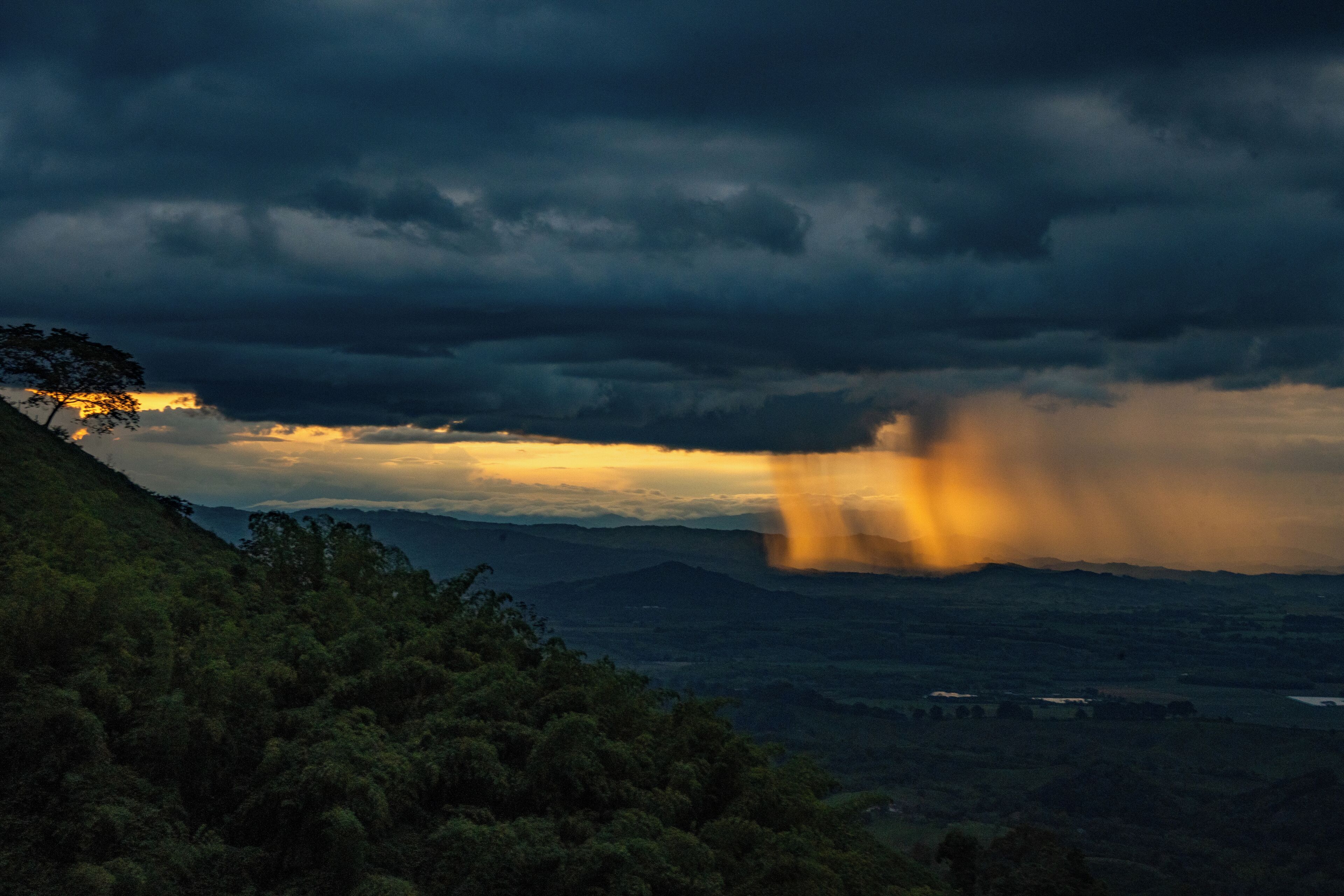 A landscape with a hill and a valley, featuring a sunset with clouds.