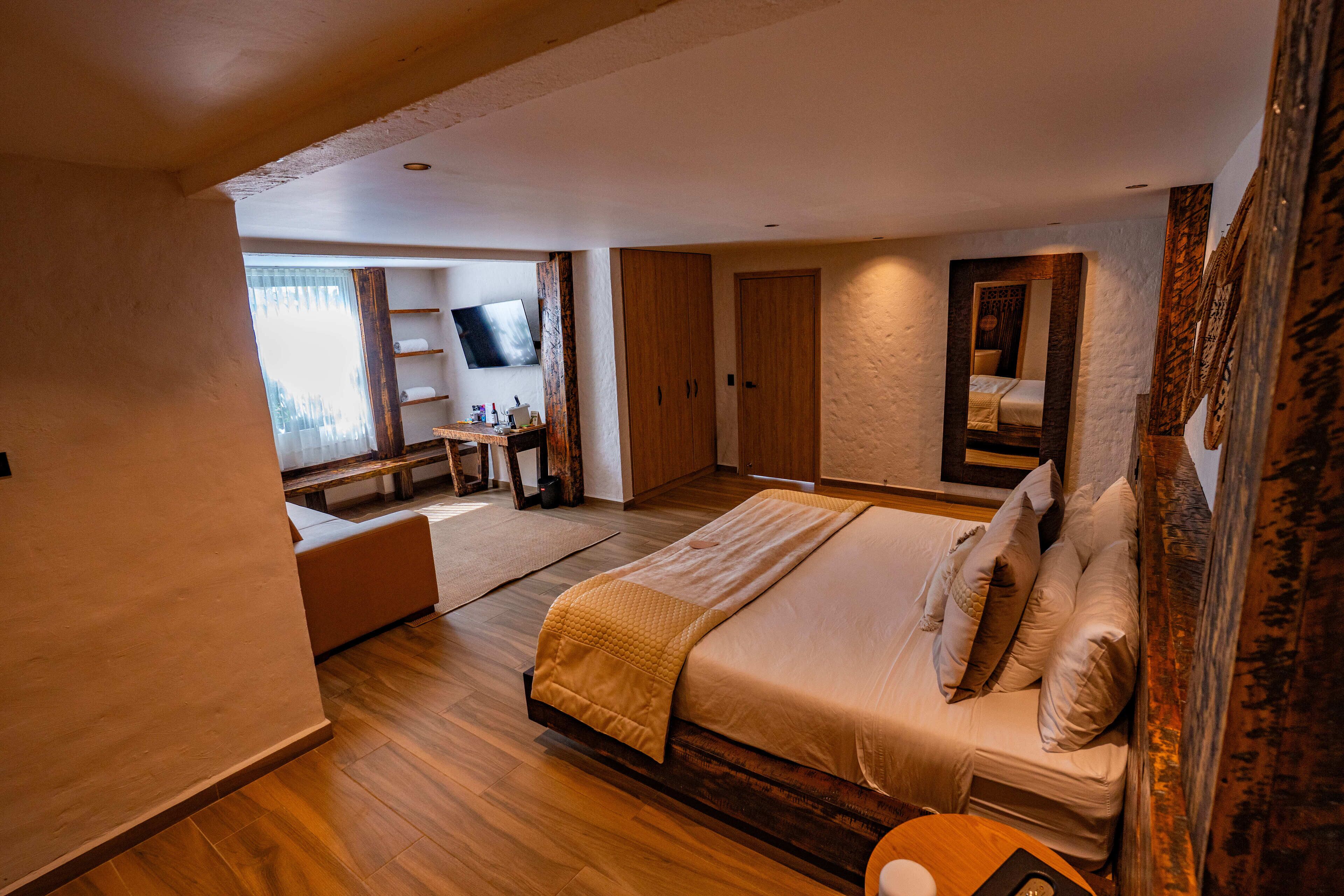 A bedroom with a large bed, a desk, a TV, and a wardrobe.