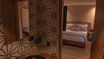 A modern bathroom with a wooden vanity, a large mirror, and a geometric-patterned wall.