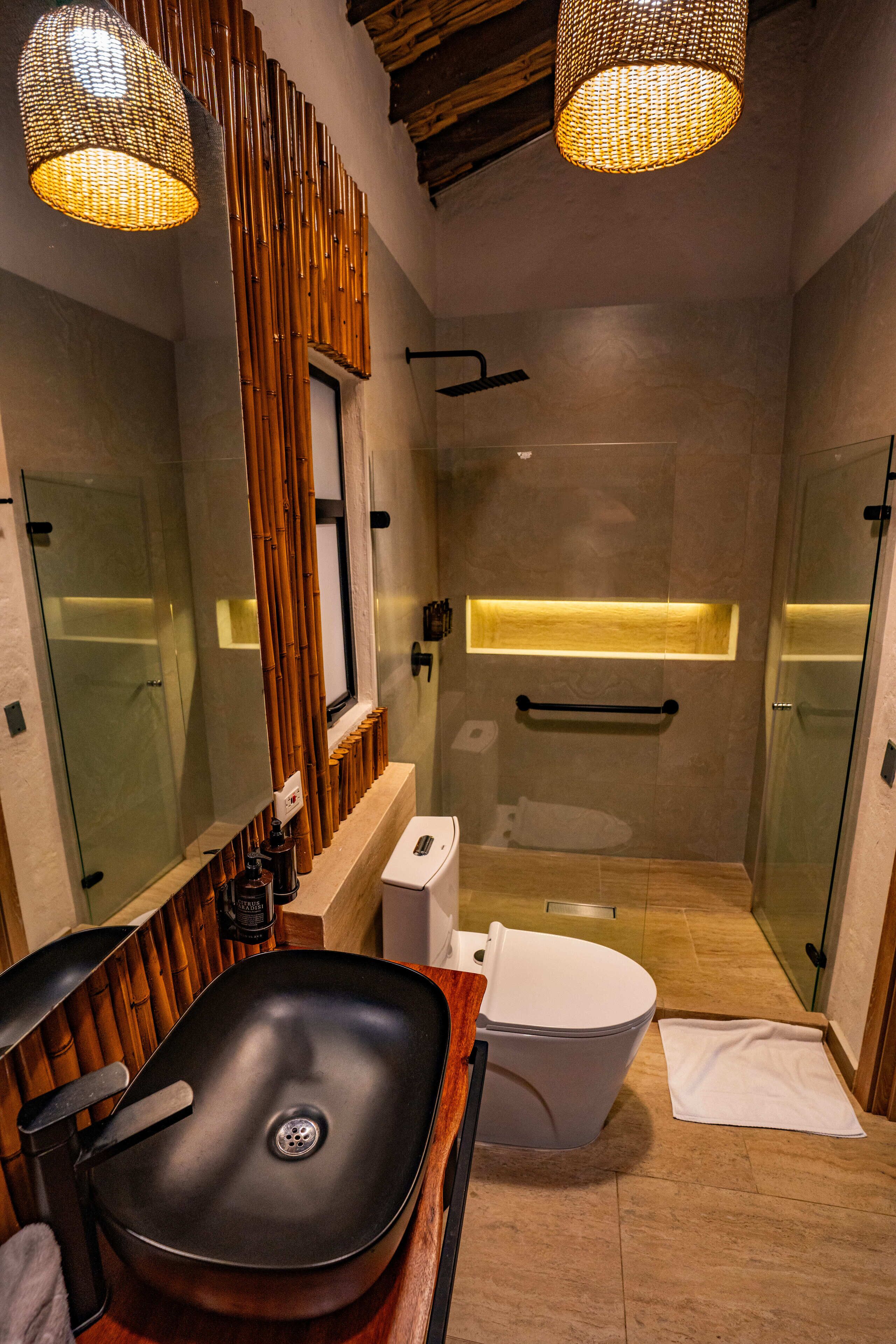 Un bany modern amb un vàter negre, vàter blanc i cabina de dutxa de vidre.