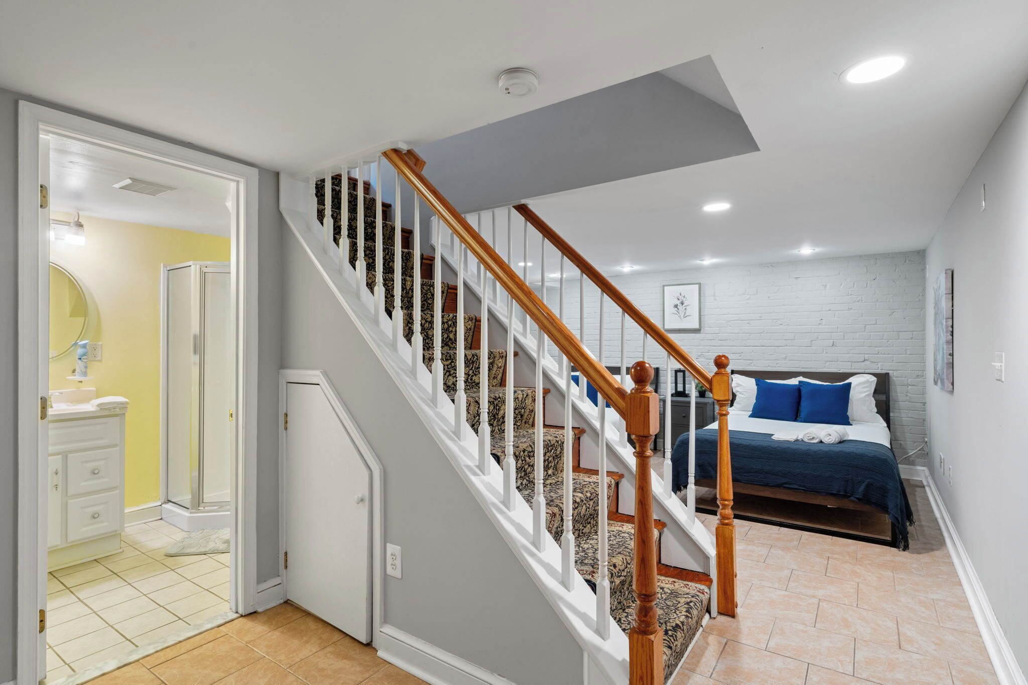 A bedroom with a bed, a bathroom with a shower, and a staircase.