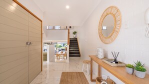 A modern interior with a staircase, a wooden bench, a mirror, and a small table with plants. - The Moorings 22, 4 Cromarty Rd - stunning townhouse with water views (Soldiers Point)