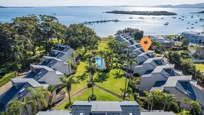 An aerial view of a resort with modern villas, a central pool, and a marina with boats. - The Moorings 22, 4 Cromarty Rd - stunning townhouse with water views (Soldiers Point)
