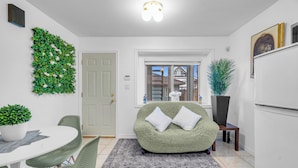 Une cuisine moderne avec un canapé vert, une table à manger avec des chaises et un mur décoratif agrémenté de plantes.