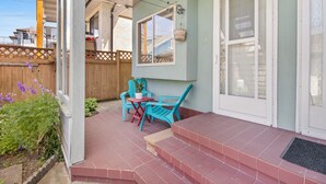 A covered patio with a small table and chairs, a wooden fence, and a door with frosted glass panels. - Mountain View Italian Villa (Vancouver)