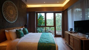 Une chambre d’hôtel moderne dotée d’un grand lit, d’un téléviseur à écran plat, d’une armoire en bois et offrant une vue sur une végétation luxuriante grâce à de grandes fenêtres.