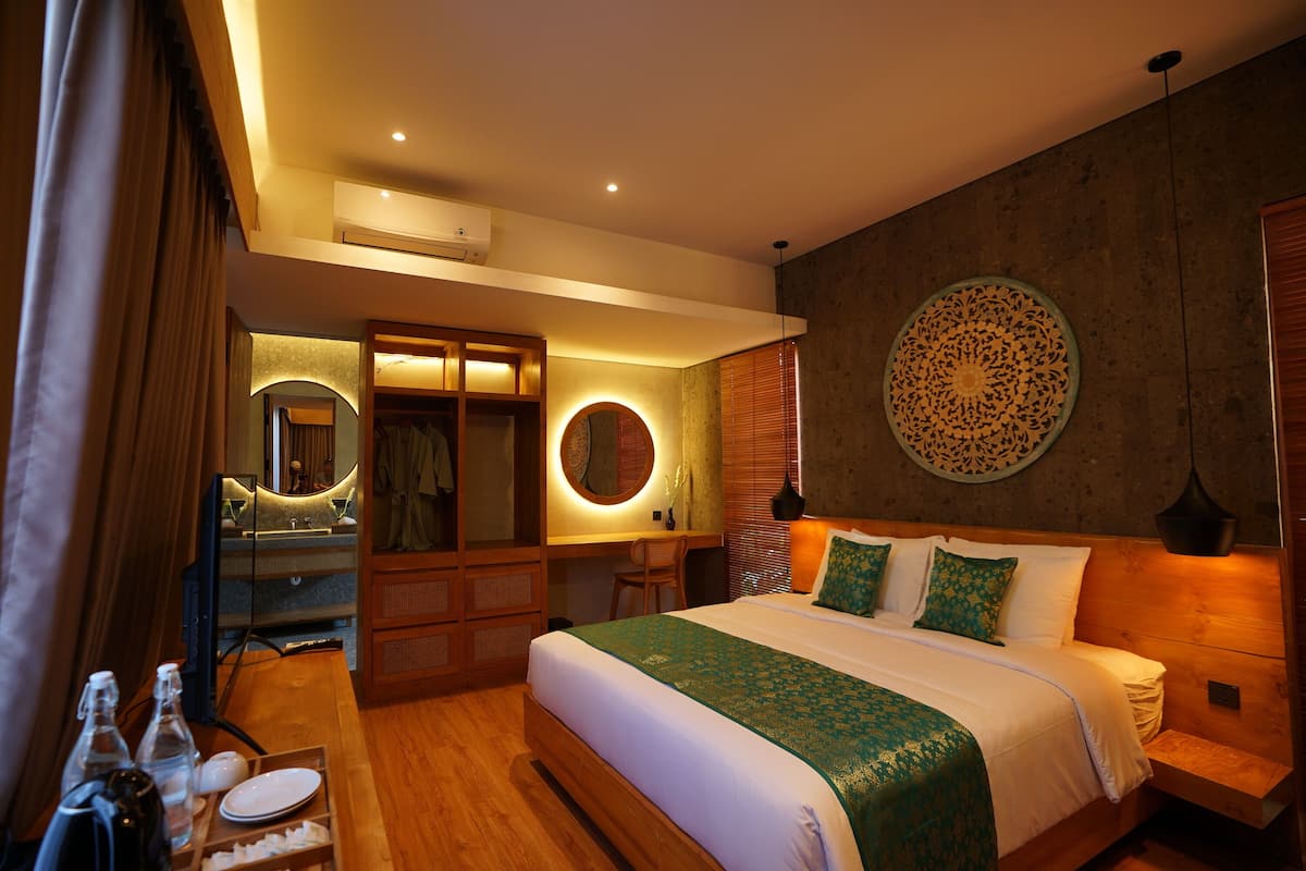 Een moderne hotelkamer met een groot bed, een kaptafel met spiegel, een houten bureau en een rond decoratief object aan de muur.