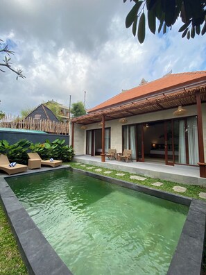 Area piscina con sedie a sdraio e patio coperto.