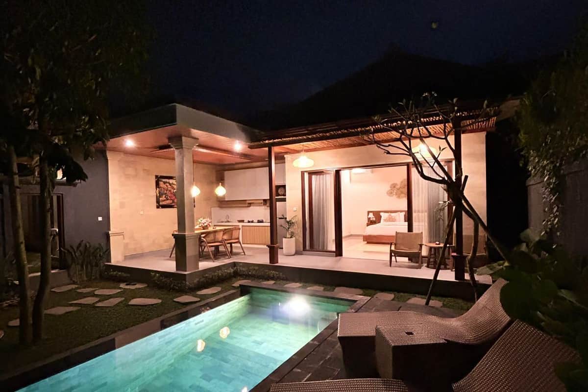 A modern outdoor pool area with a lounge chair and a covered seating area.