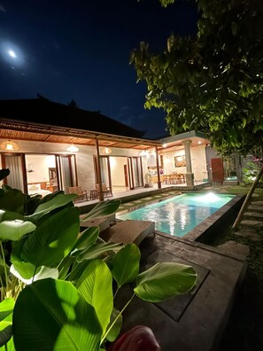 A modern house with a swimming pool, large windows, and a well-lit patio area. - Ghauri Green View Villas by EPS (Ubud)