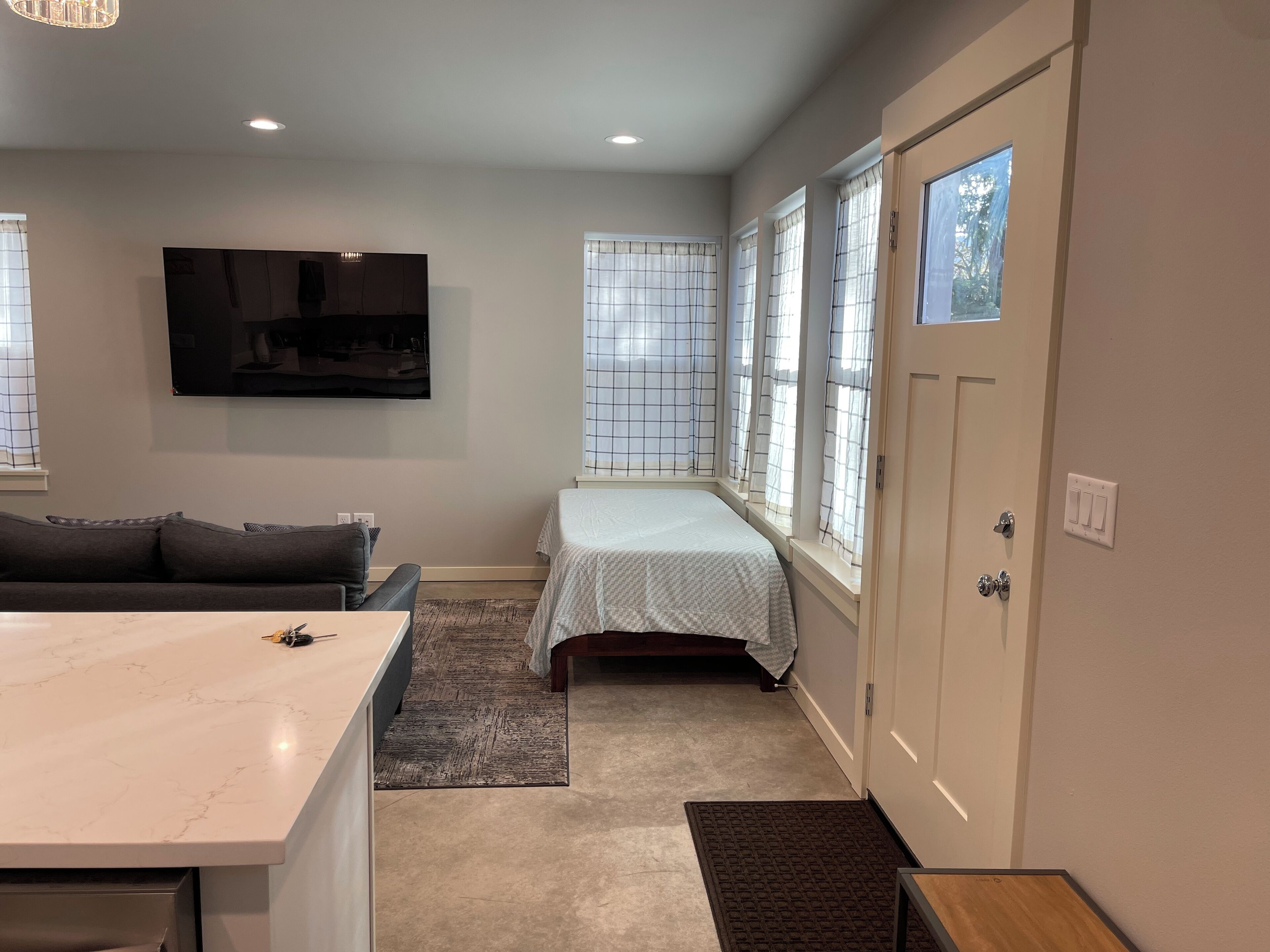 A compact living space with a sofa, a bed, a TV, and a dining area.