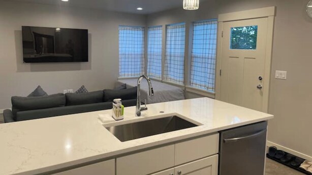 A modern kitchen with a large island, a built-in sink, and pendant lighting. - Kamal's Comfy Relaxation Zone (Eugene)