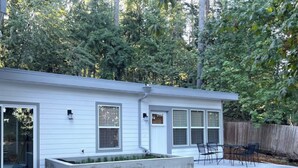 A single-story house with a patio area, a small garden bed, and a wooden fence. - Kamal's Comfy Relaxation Zone (Eugene)