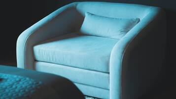 A modern armchair with a cushion in a dimly lit room.
