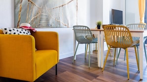 A modern living room with a yellow sofa, a dining table with chairs, and a large abstract painting on the wall. - 327 Parque Santiago II, sea view, 2 bedroom, 2 bathroom, wifi (Playa de las Américas)