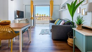 A modern living room with a dining area, a TV, and a balcony with yellow curtains. - 327 Parque Santiago II, sea view, 2 bedroom, 2 bathroom, wifi (Playa de las Américas)