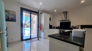 A modern kitchen with white cabinets, a black countertop, and a stainless steel range hood. - Superb villa with a private pool (Saint-Nazaire-d'Aude)