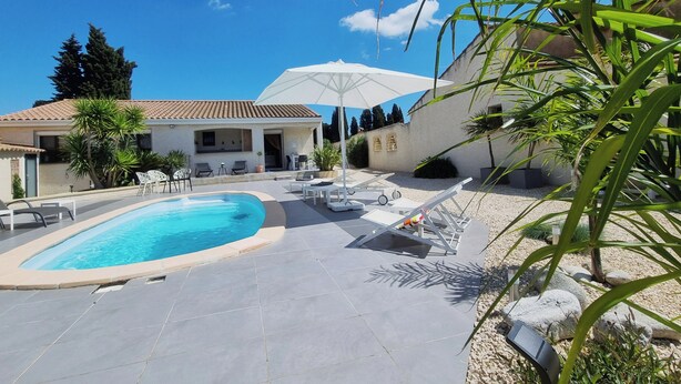 A pool area with a clear blue pool, lounge chairs, and umbrellas. - Superb villa with a private pool (Saint-Nazaire-d'Aude)