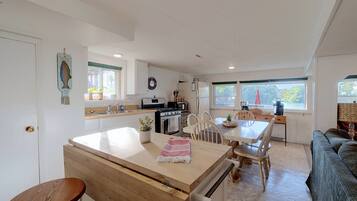 A modern kitchen with a central island, wooden chairs, and a dining table.