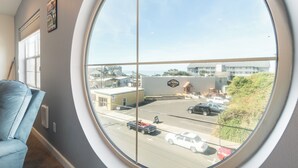 A room with a large round window offering a view of a parking lot and buildings outside. - Oceanic Mirage - Newly Remodeled Family Friendly Ocean View (Newport)