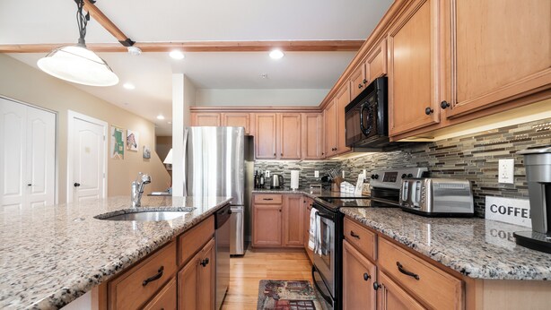 A kitchen with granite countertops, wooden cabinets, stainless steel appliances, and a tiled backsplash. - Oceanic Mirage - Newly Remodeled Family Friendly Ocean View (Newport)