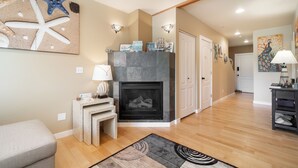 A living room with a fireplace, wooden flooring, and a rug. - Oceanic Mirage - Newly Remodeled Family Friendly Ocean View (Newport)