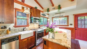 Cocina con gabinetes de madera, encimeras de granito, electrodomésticos de acero inoxidable y una puerta roja.