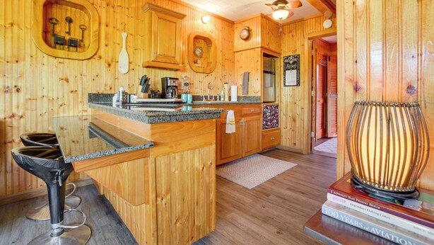 Un intérieur en bois comprenant un coin cuisine, des tabourets de bar et une lampe décorative.