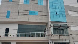 A modern building with a flat roof, large windows, and a gated entrance. - Hotel Paramount (Visakhapatnam)