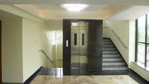 A modern interior with a marble floor, a staircase with a handrail, and a large window providing natural light. - Hotel Paramount (Visakhapatnam)