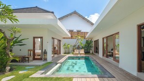 A modern house with a swimming pool, wooden deck, and lush greenery.