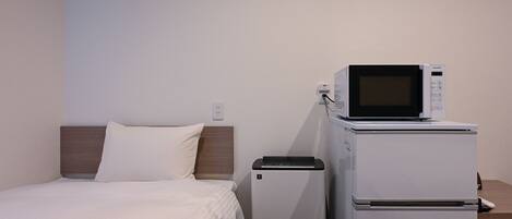 A hotel room with a bed, a microwave, and a refrigerator.