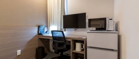 Habitación de hotel con escritorio, televisión de pantalla plana, microondas, cafetera y refrigerador pequeño.