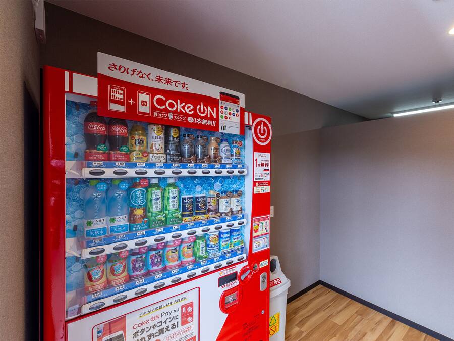 A vending machine with various drinks and snacks, a Coca-Cola sign, and a target sign on the wall.
