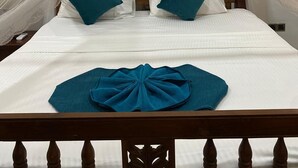 Un lit recouvert d’une couvre-lit blanche, avec deux coussins turquoise et un coussin décoratif bleu.