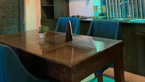 Une cuisine avec des meubles de rangement en bois, une table à manger, des chaises et un ventilateur de plafond.