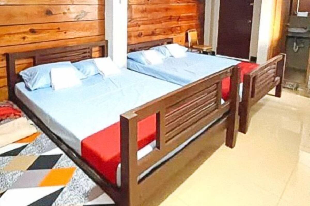 Un lit en bois avec un matelas bleu et des oreillers rouges, dans une pièce aux murs en bois.