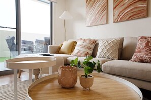 A modern living room with a round wooden coffee table, a small potted plant, and a sofa with patterned cushions. - Ground Level 1-Bed: Courtyard & Alfresco Dining (Wright)
