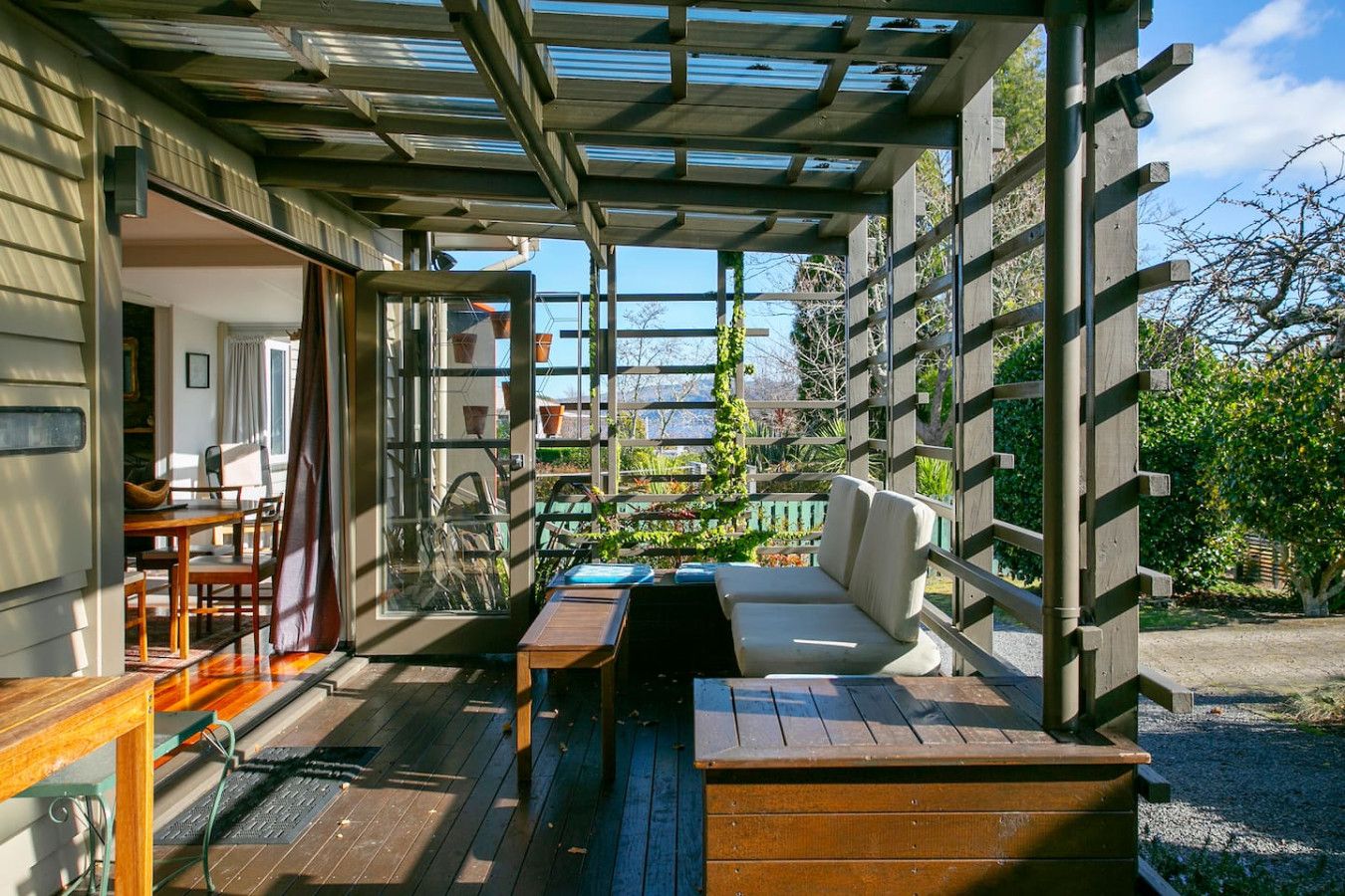 A covered outdoor seating area with a wooden bench, a table, and a sofa.