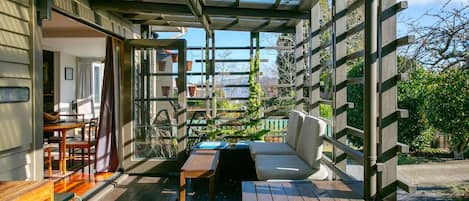 A covered outdoor seating area with a wooden bench, a table, and a sofa.