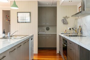 A modern kitchen with a central island, wooden flooring, and a hanging pendant light.